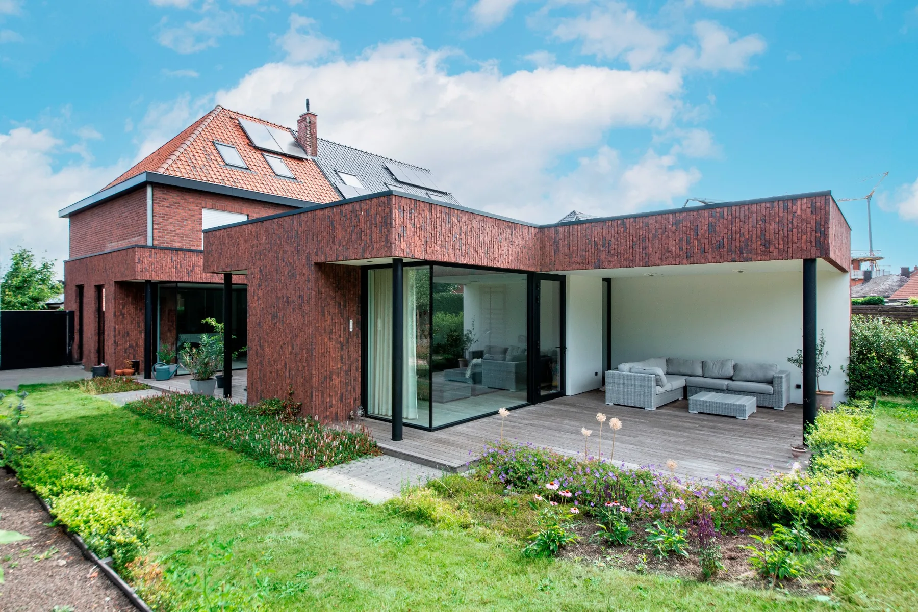 Architecturale woonuitbreiding met grote glaspartijen en overdekt terras